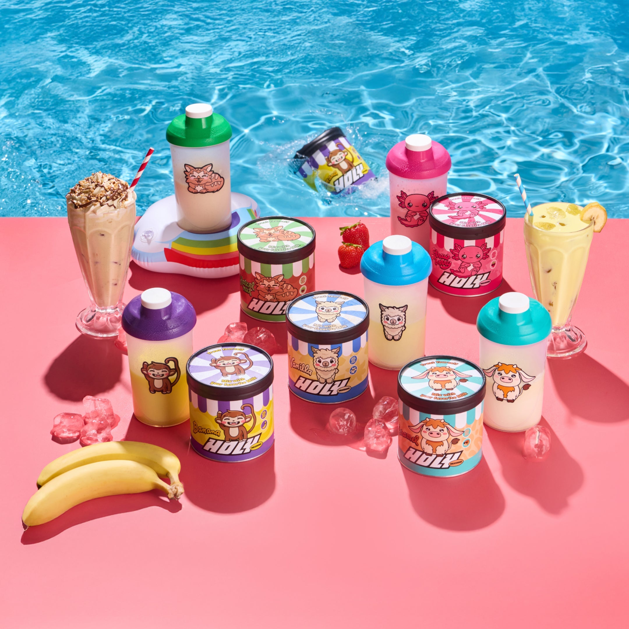 Pappdosen und Shaker mit bunten Motiven stehen auf einem Tisch am Pool, umgeben von Getränken, Eis und Bananen.
