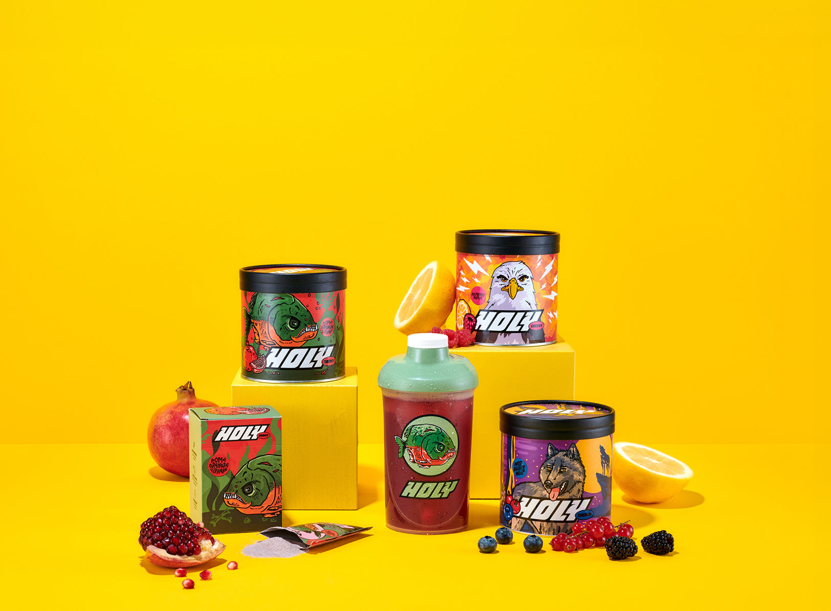 Verschiedene bunte Pappdosen und ein Shaker auf gelbem Hintergrund, umgeben von Früchten und Sachets.