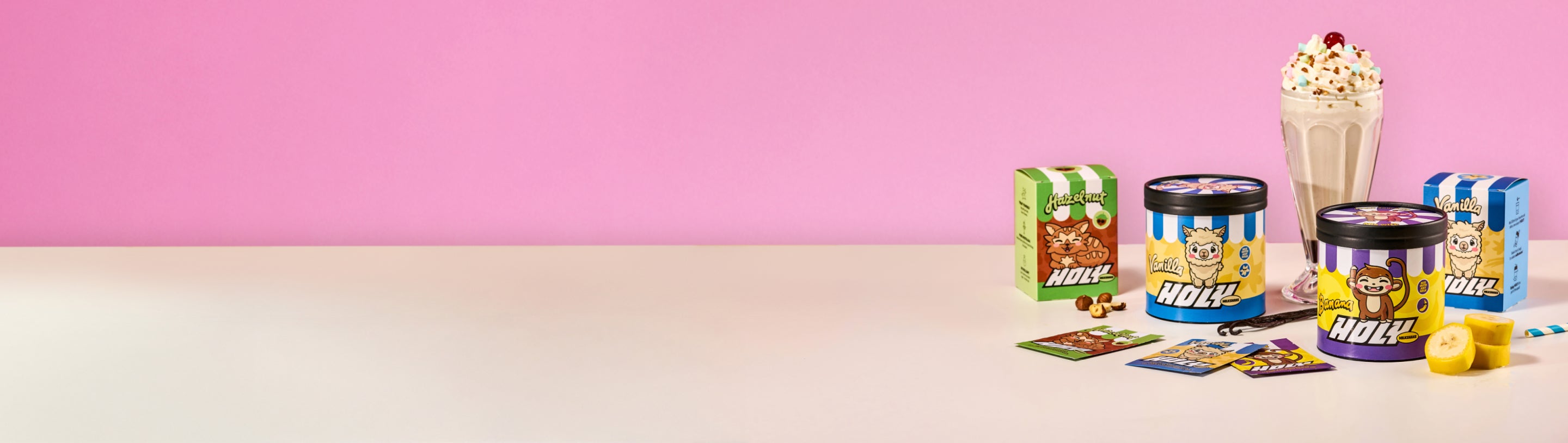 Verschiedene Pappdosen und Probepackungen mit Shaker auf rosa Hintergrund, umgeben von Bananen und Nüssen.