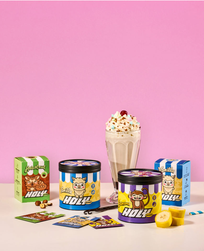 Pappdosen, Probepackungen und ein Milchshake vor einem pinken Hintergrund.