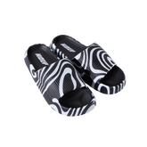 Schwarz-weiße Pantoletten mit geschwungenem Muster auf schwarzem Hintergrund.